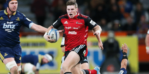 Colin Slade bursts through a hole in the Crusaders' narrow victory over the Highlanders. Photo / Getty