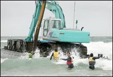 Workers try to secure a barge with digger aboard being used to build a surf reef in Mt Maunganui. Picture / Alan Gibson Workers try to secure a barge with digger aboard being used to build a surf reef in Mt Maunganui. Picture / Alan Gibson