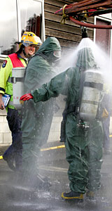 Senior Firefighter Chris Brown helps wash colleague Firefighter Tarah Whitehead in their Level 3 Decontamination suits. Photo / Janna Dixon Senior Firefighter Chris Brown helps wash colleague Firefighter Tarah Whitehead in their Level 3 Decontamination suits. Photo / Janna Dixon