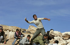 A Palestinian hurls a stone as others take cover during clashes with Israeli troops at a demonstration against Israel's military operation in Gaza. Photo / AP A Palestinian hurls a stone as others take cover during clashes with Israeli troops at a demonstration against Israel's military operation in Gaza. Photo / AP