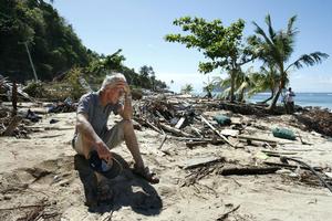 Andy Belcher sits among the devastation on a beach in southeast Samoa. Photo / Brett Phibbs
