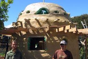 Alex Grey and Bomun Bok-Chung in front of the 'Earth Bag' building they helped make at the Solscape eco-resort in Raglan.