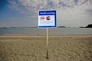 A warning sign on a beach tells people to stay out of the water due to a sewage overflow. Photo / Dean Purcell