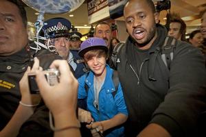 Justin Bieber is dwarfed by police and security staff as he is rushed past fans at Auckland airport last night. Photo / Richard Robinson