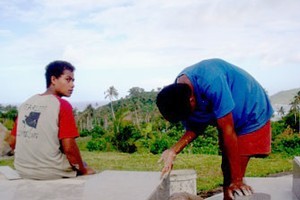 Boys add finishing touches to the newly tiled graves of tsunami victims, in preparation for a memorial on the 29th. Photo / Cherelle Jackson