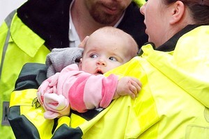 An injured baby is carried by a St John medic to an ambulance after the tornado struck Albany. Photo / Sarah Ivey