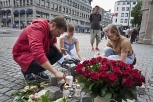 People light candles and lay flowers in central Oslo to pay tribute to the victims of the twin attacks which left over 90 people dead. Photo / AFP