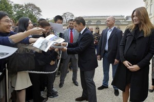 A heavily-pregnant Carla Bruni-Sarkozy (R) looks on as her husband, French President Nicolas Sarkozy, signs autographs in the gardens of the Elysee Palace in Paris. Photo / AFP