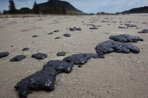 Oil from the stricken ship, Rena, has begun washing up on the beach at Mount Manguanui. Photo / SNPA/John Cowpland
