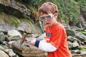 Jamie Tully checks out an interesting rock in his quest for fossils at Kiritehere Beach. Photo / Alex Tully