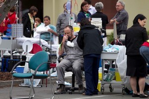 Injured residents are tended to in the carpark of a 24 hour surgery on Bealey Ave in Christchurch after the 6.3 earthquake. Photo / Simon Baker