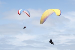 The writer and his training buddy paraglide over Kariotahi beach. Photo / Supplied
