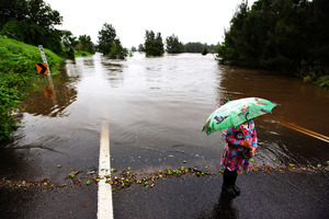 Locals look on as the waters of the Hawkesbury River continue to rise completely covering the Yarramundi Bridge. Photo / Getty Images