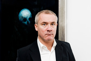 Artist Damien Hirst posing in front of his painting 'Floating Skull'. Photo / Supplied