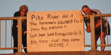 Anna Osborne and Tom Daly put up a sign on the Cobden Bridge protesting the lack of progress in recovering loved ones' bodies. Photo / Greymouth Star.