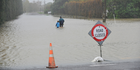 Grant Watson and his son Luke wade home through the flood waters just north of Gisborne after heavy rain. Photo / Gisborne Herald