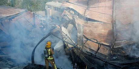 A fireman damps down hotspots at the barn that housed the 1968 Corvette Stingray. Photo / Christine Cornege