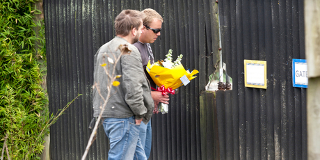 Two men take a floral tribute to Franklin Zoo, which has also received messages of support and donations. Photo / Dean Purcell