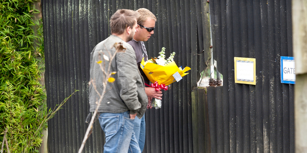 Two men take a floral tribute to Franklin Zoo, which has also received messages of support and donations. Photo / Dean Purcell