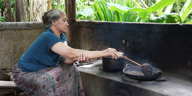 A woman roasts beans to make kopi luwak, after they've been conveniently processed by the Asian palm civet. Photo / Kieran Nash