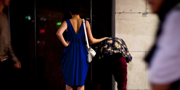 A girl rubs a man's back while he vomits. Photo / Dean Purcell