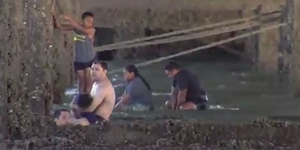 Survivors of a boating accident in Manukau Harbour cling to Manukau Bridge.