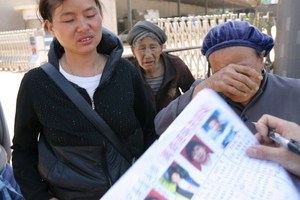 Family members with photos of their missing relatives in Nanmen. Photo / AFP