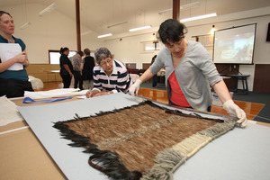 Rangi Te Kanawa inspects an old cloak belonging to Audrey Harris (on her left) at the NorthTec marae in Raumanga. Photo / APN