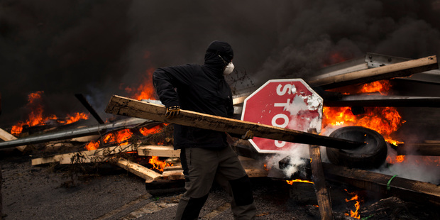 A striking miner tends to a burning barricade during a strike in Oviedo, Spain. NZ is committing to lend the IMF $US1b in case of an economic meltdown such as that threatening Europe. Photo / AP