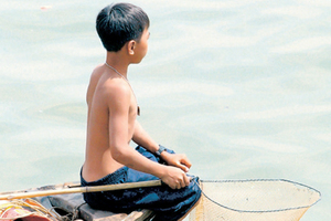 A Vietnamese boy fishes for turtles on the Saigon River, just metres from the streets of Ho Chi Minh City. Photo / Bay of Plenty Times
