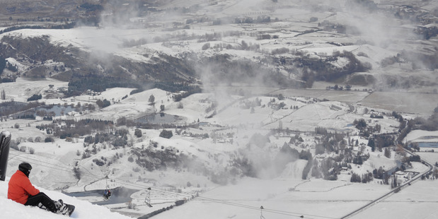 A snowboarder takes in the snow covered landscape of Queenstown from Coronet Peak today. Photo / Supplied NZSKI
