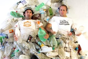 Camden Howitt and Sam Judd lying in less than one-fifth of the plastic bottles picked-up by volunteers in one day, from the shores of uninhabited Rangitoto Island. Photo / Supplied