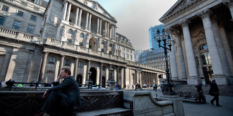 A businessman outside the Bank of England, left. The Bank of England is widely expected to announce another wave of monetary easing tomorrow, alongside the European Central Bank. Photo / Bloomberg
