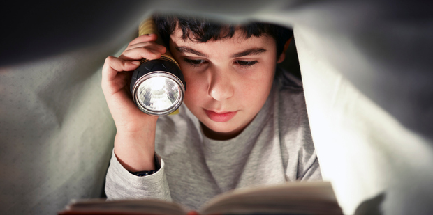 Reading under the cover of darkness may not protect children from bleak tales of lost childhoods found through the portal of their story books. Photo / Thinkstock