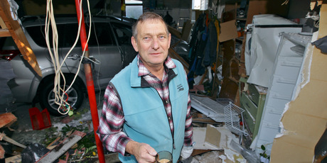John Pingram surveys the damage to his garage caused by property developer Jonathan King's car crashing into it. Photo / Michael Craig