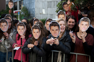 Female fans holding masks of their idol gather outside the Langham Hotel in Auckland hoping to see Canadian pop star Justin Bieber. Pictures / Greg Bowker