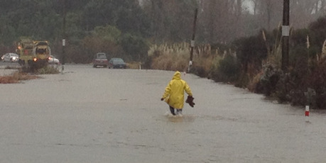 A man wades in flood conditions on the Waihi Beach Road off State Highway 2 today. Photo / Alan Gibson