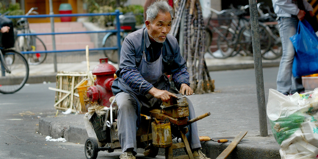 An elderly man sharpens knives on the roadside in Old Shanghai. Photo / Kenny Rodger