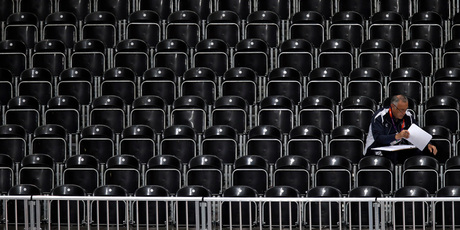 A lone man sits in an empty section of seats inside Earls Court during during a women's volleyball preliminary match between China and Turkey on Monday. Photo / AP