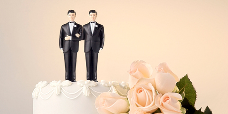 Still life of the top of a wedding cake with two miniature grooms cake topper and roses at the side