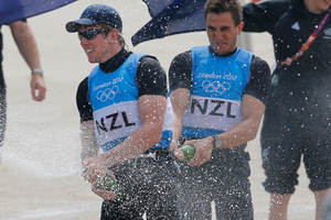 Peter Burling and Blair Tuke of New Zealand spray champagne to celebrate their silver medal of the 49er men sailing race. Photo / Francois Mori.