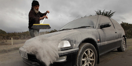 Vic Cassin sweeps ash from one of the vehicles parked on his section south of Turangi, which was in the path of the ash cloud from last night's eruption of Mt Tongariro. Photo / Alan Gibson