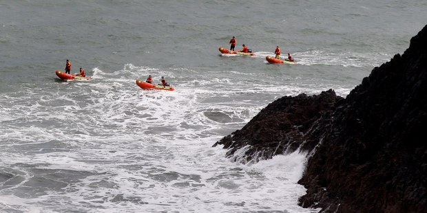 Rescue boats search the seas around Paritutu Rock yesterday for the two students and instructor missing since plunging from the rock into stormy seas on Wednesday. Photo / Christine Cornege