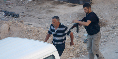 A Syrian rebel fighter detains a man at an improvised checkpoint in Damascus. The Syrian army says it controls all of the capital. Photo / AP