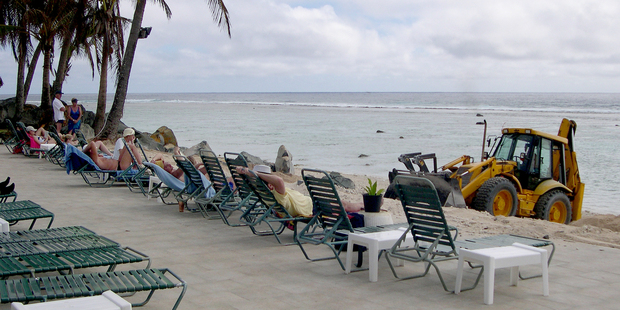 A bulldozer at the Edgewater Resort restores the beach while tourists enjoy the sun. Photo / Jim Eagles
