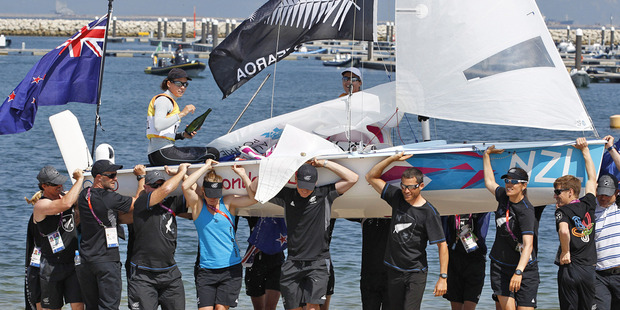 Jo Aleh, left, and Olivia Powrie and their dinghy are carried ashore by members of the New Zealand sailing team after winning gold medal women's 470. Photo / Mark Mitchell