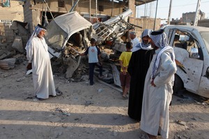 Iraqis inspect the aftermath of a car bomb that exploded near the town of Suwayrah. Photo / AP