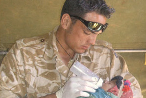 Lance Corporal Luke Tamatea feeding a baby nutrient formula. Photo / Supplied