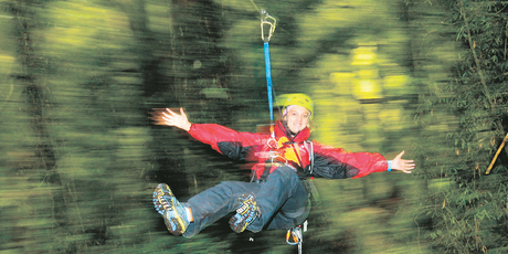 Rotorua Canopy Tours guide Alex Barr enjoys a ride on New Zealand's first zip-line tour through the native tree canopy. Photo / Alan Gibson