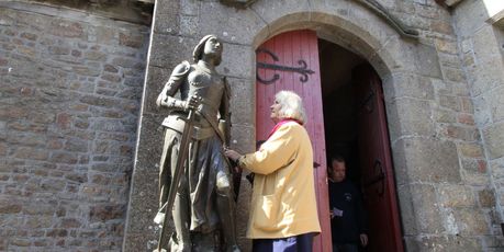 A woman addresses the statue of Joan of Arc outside the parish church on Mont St Michel. Photo / Jim Eagles